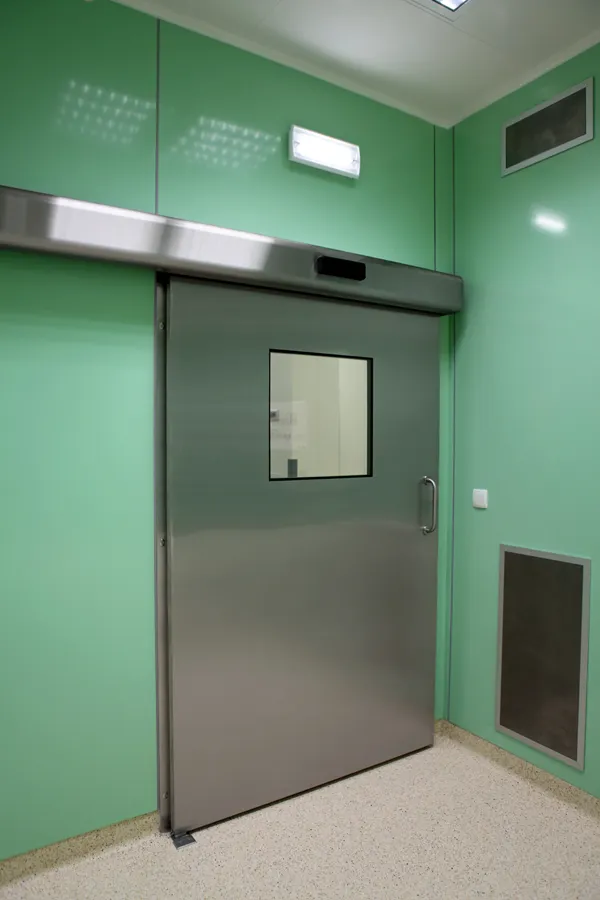 Puerta corrediza antibacteriana de Wiejak Med, instalada en un hospital con pared verde pistache, ideal para mantener áreas estériles y libres de microorganismos.