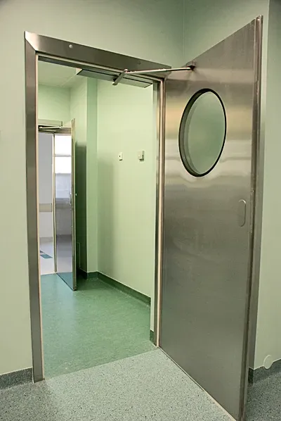Puerta hermética de apertura automática con visor redondo y sistema de sellado.